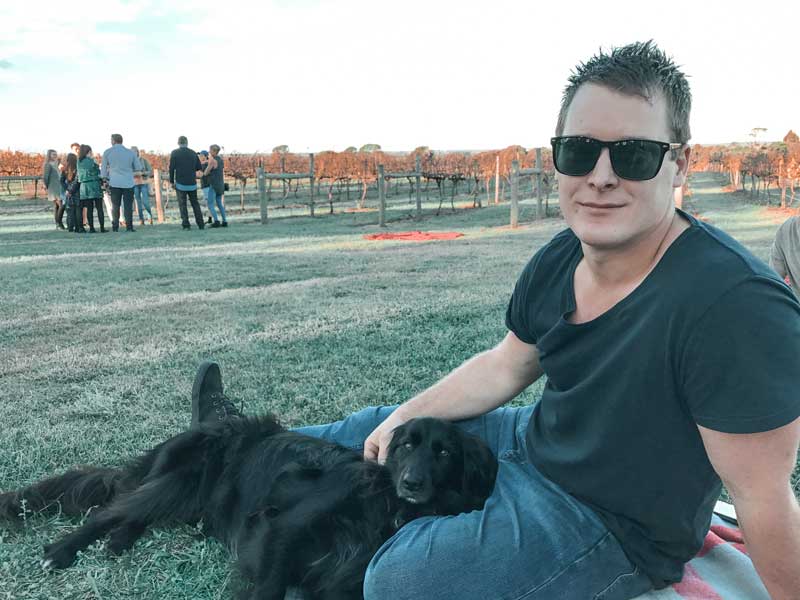 Gippsland dog-friendly winery Avon Ridge Maffra >> Man laying on a picnic rug with his dog and grape vines in the background