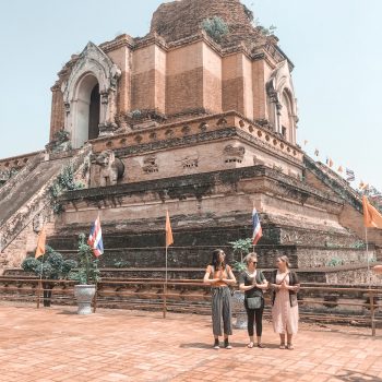 Three girls standing in a Buddhist Pose in front of the Chedi Luang Stupa in Chiang Mai, Thailand